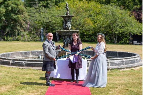 Couple at altar tying the knot with fountain in background